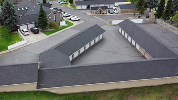 A parking lot with a few cars and a building with a grey roof.